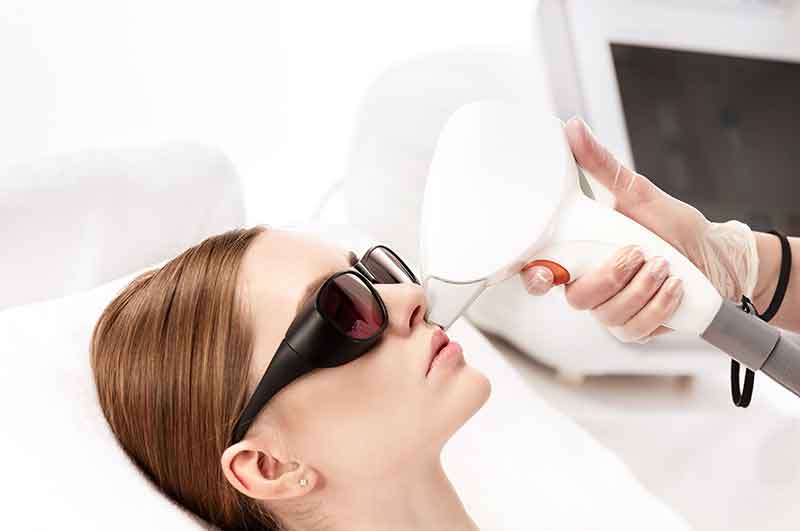 young woman receiving laser treatment on face isolated on white. laser skin care